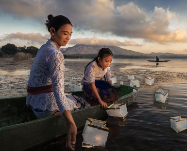 Mom and daughter launch lanterns on the lake on the Festival of the Goddess of Rice in Bali. In front of the volcano Batur.Indonesia